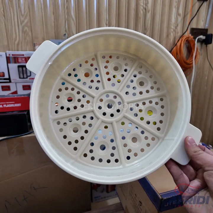 A round, light-colored plastic steamer basket with a perforated bottom and two small handles.