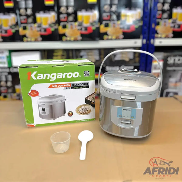 A silver and white rice cooker, 1.8L capacity, with its original green and white packaging, and accompanying measuring cup and spoon.