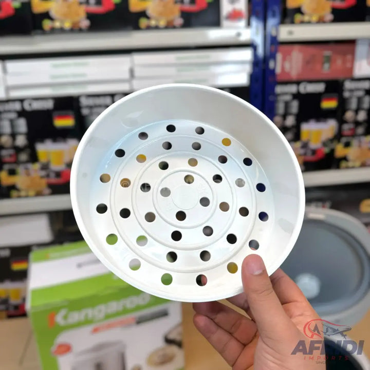 White plastic steamer basket with circular holes for a rice cooker.