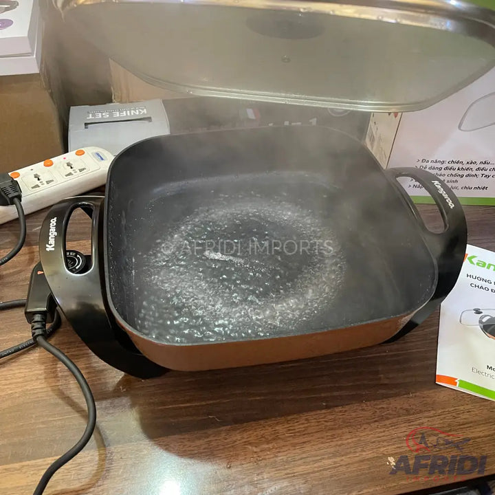 An electric cooking pot with boiling water and an open lid.