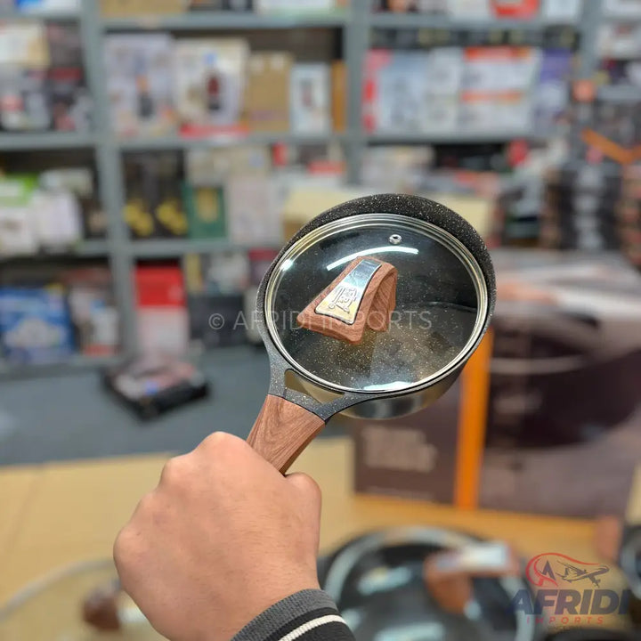 A black non-stick frying pan with a wooden handle and a clear glass lid.