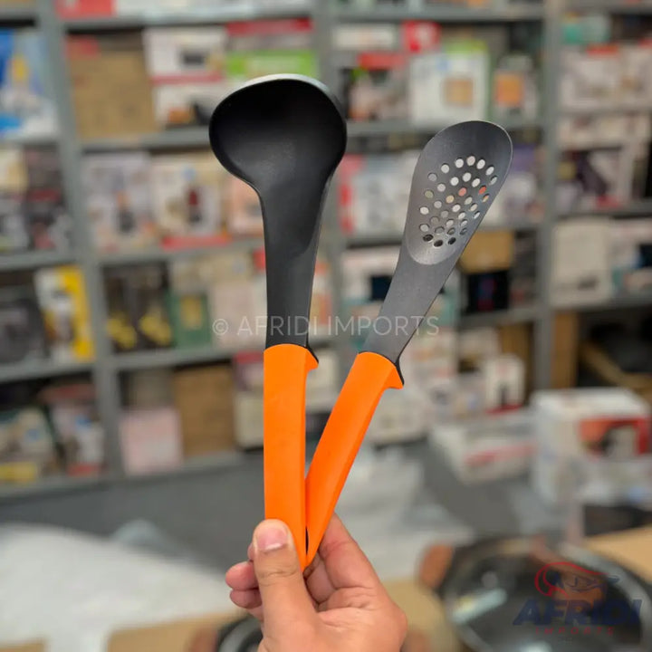 Two kitchen utensils with black heads and orange handles, one a ladle and the other a slotted spoon.