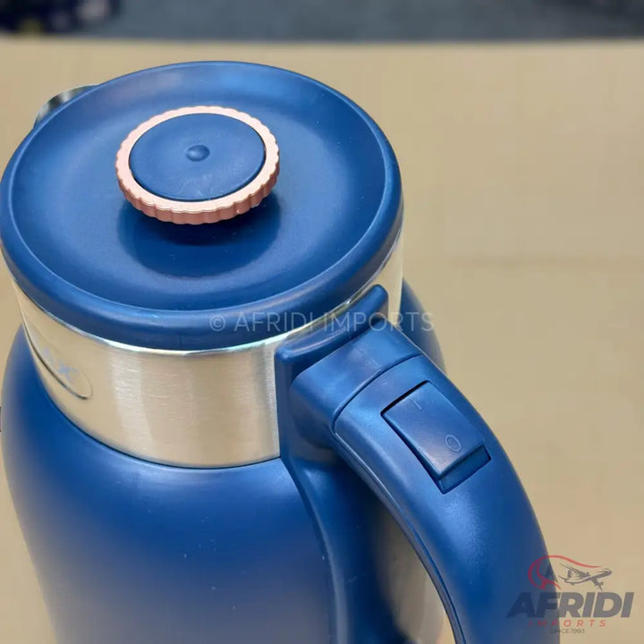 A blue and silver electric kettle with a circular copper-colored accent on the lid and a switch on the handle.