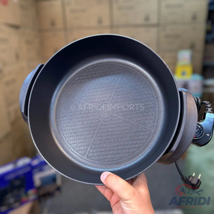 A black electric skillet with a textured non-stick cooking surface and a detachable power cord.
