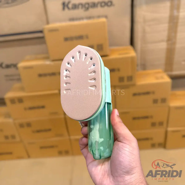 A handheld portable garment steamer with a light green water tank and a beige soleplate with steam vents.