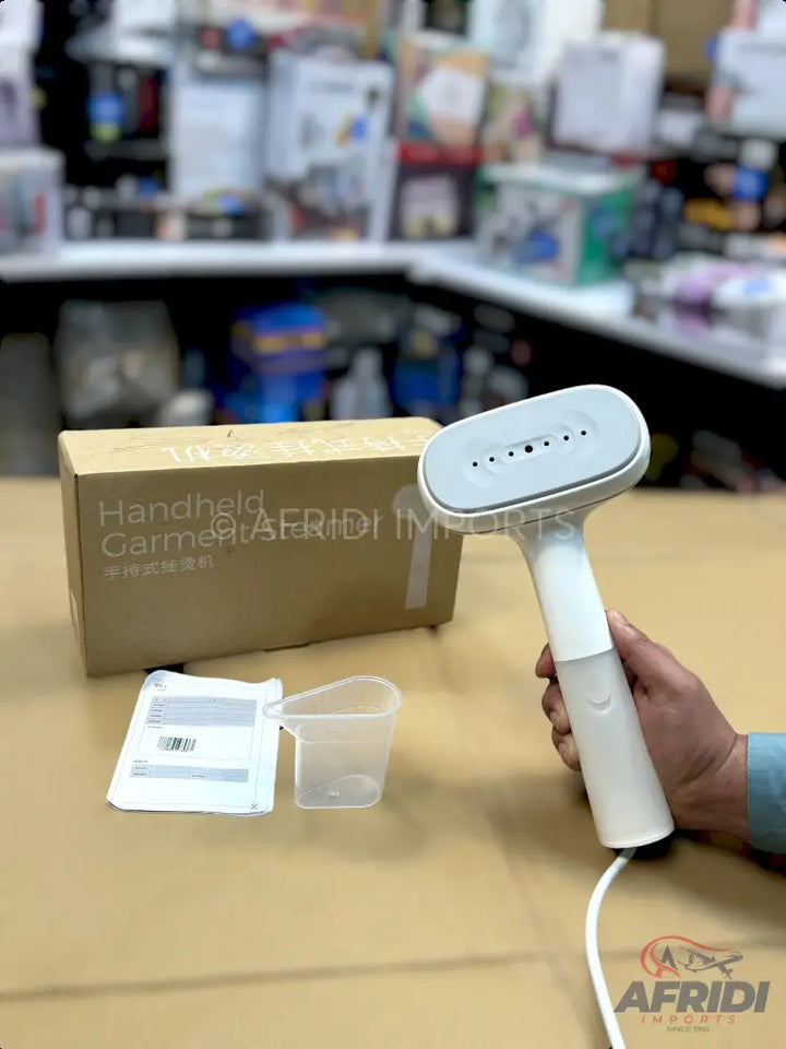 White handheld garment steamer with a flat, perforated head.