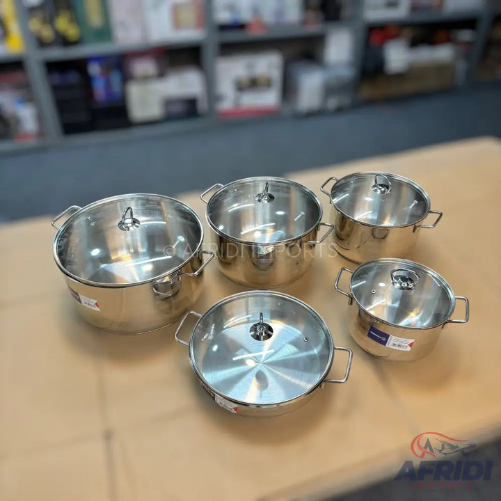 A set of five stainless steel pots with clear glass lids.