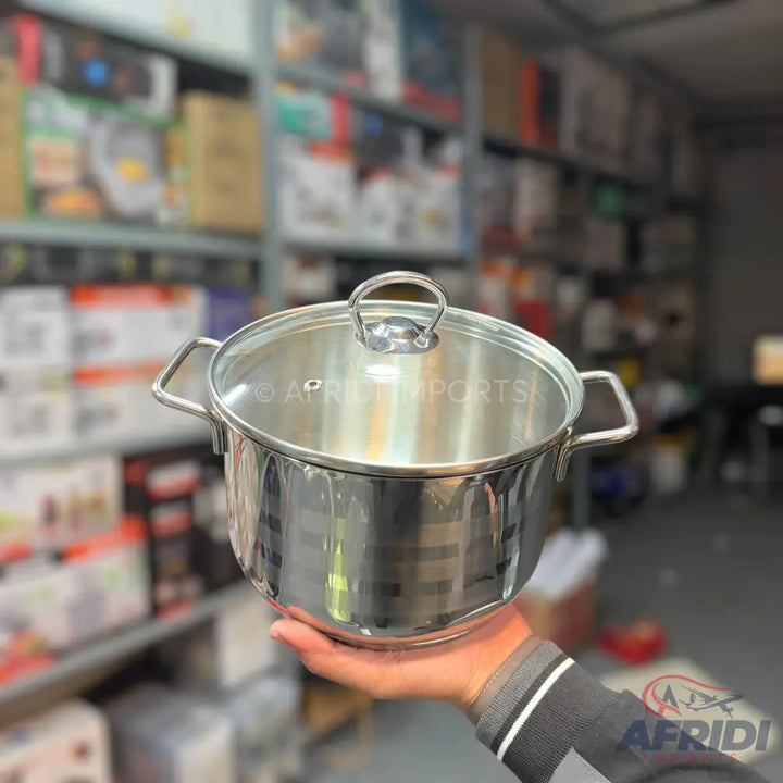 Shiny stainless steel cooking pot with a glass lid and two side handles.