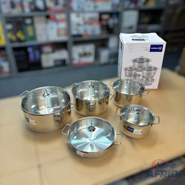 A set of six shiny stainless steel pots and pans with clear glass lids.