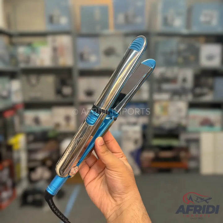 Shiny silver and blue hair straightener held in a hand.