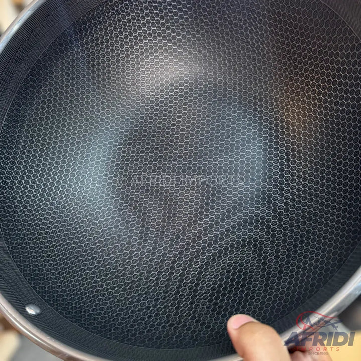 A dark grey non-stick cooking pan with a hexagonal textured surface.