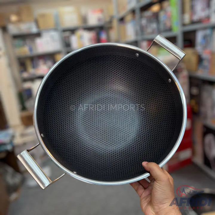 A black non-stick wok with a honeycomb pattern and two silver loop handles.