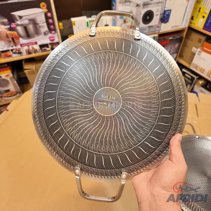 A stainless steel frying pan with a textured induction-compatible base and two side handles.