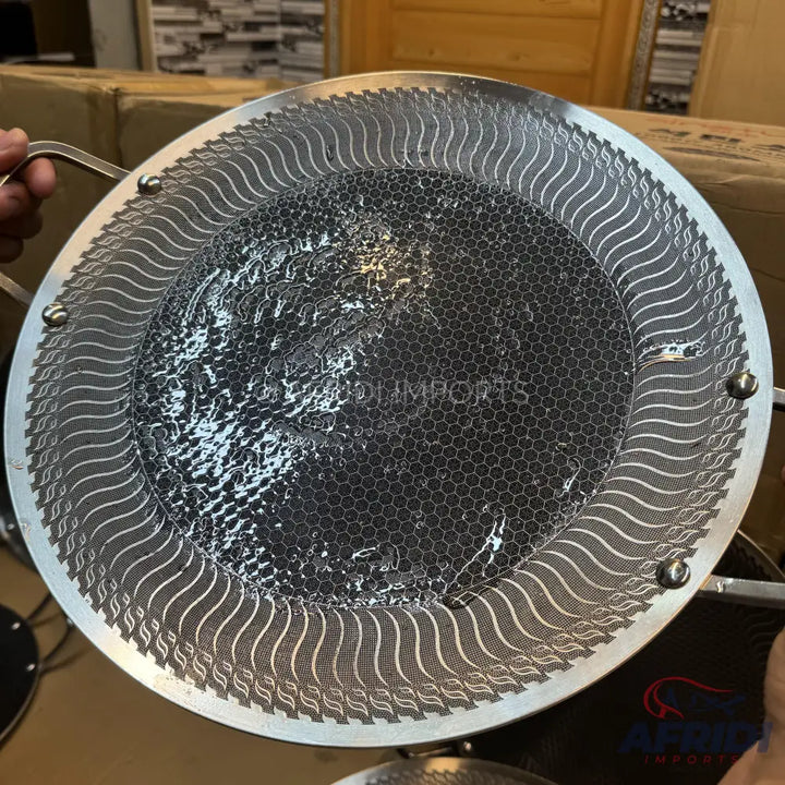 A circular cooking pan with a honeycomb-patterned non-stick surface and an embossed wavy design on the rim.