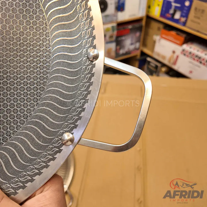 Stainless steel frying pan with a honeycomb and wave-patterned non-stick surface and a riveted loop handle.