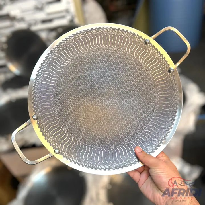 Round metal frying pan with a textured cooking surface and two handles.