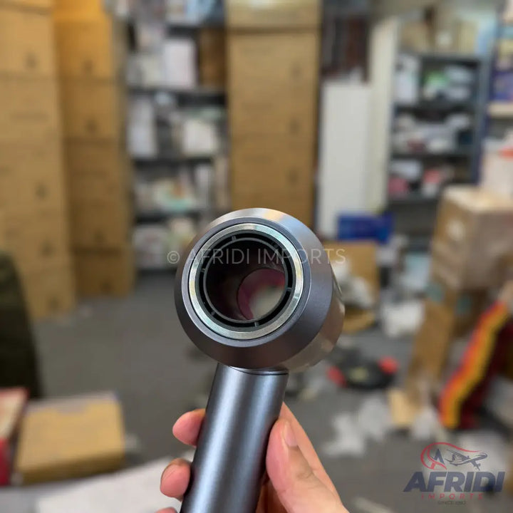 A dark gray, sleek, and modern hair dryer, held by a hand.