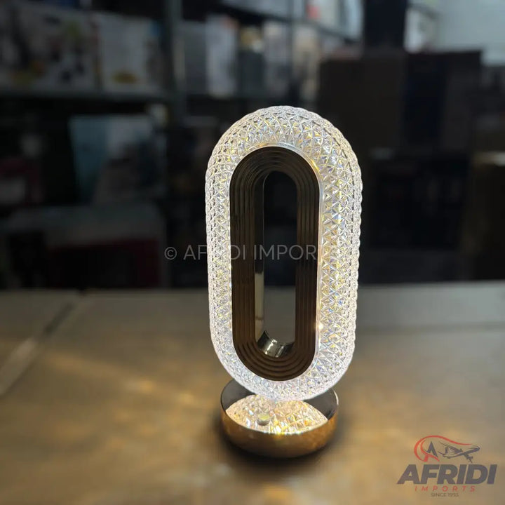 Modern crystal LED table lamp with an oval, open-frame design.