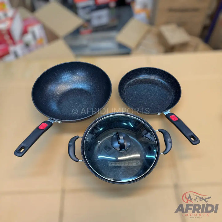 Set of black non-stick cooking pots and pans with heat-resistant handles and a glass lid.