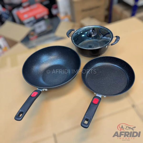 A set of three black non-stick cooking pots and pans with red and black handles.