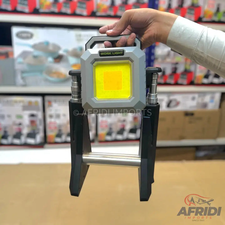 A portable, adjustable work light with a bright yellow LED panel and a sturdy carrying handle.