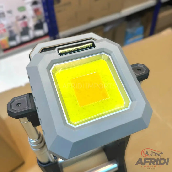 Grey portable work light with a bright yellow LED panel.