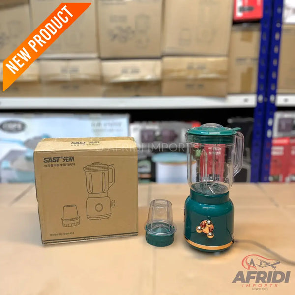 A green blender with a clear pitcher, an additional small cup, and its cardboard packaging.