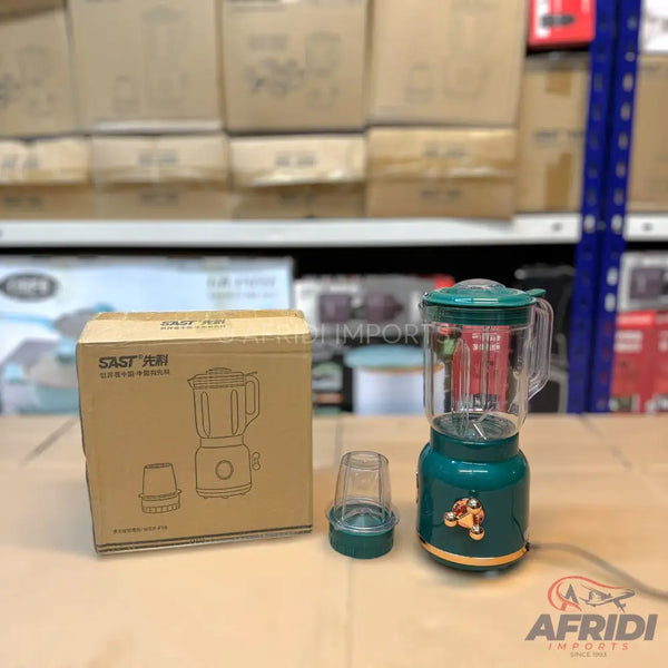 A green blender with a clear pitcher, an additional small cup, and its cardboard packaging.
