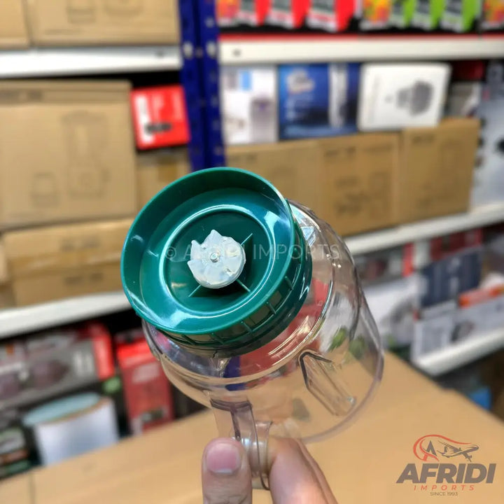 A clear plastic blender cup with a dark green lid and a white blade assembly.