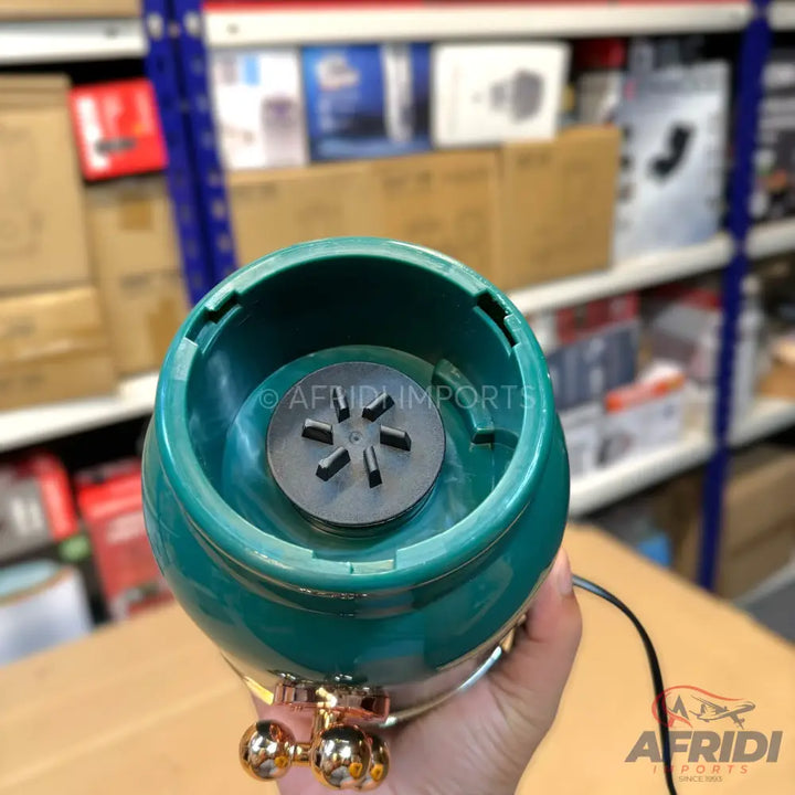 A teal-colored portable blender base with a six-pronged blending mechanism.