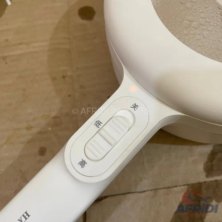 White electric cooking pot with boiling water and a control switch.