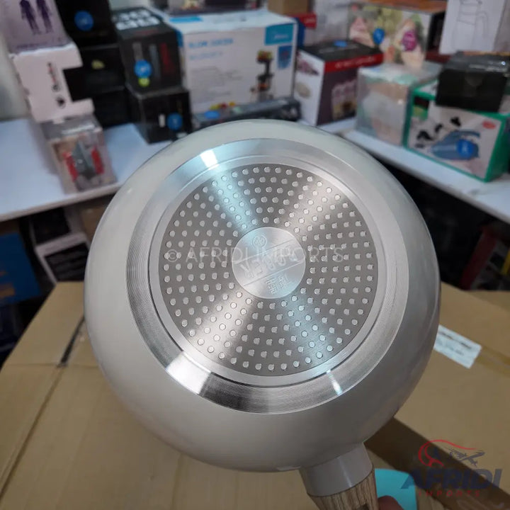 Underside of a light-colored nonstick frying pan with a textured induction-compatible base.