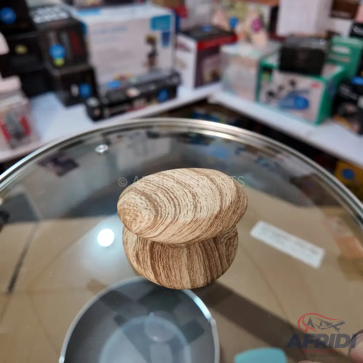 A glass pot lid with a light brown, wood-grain patterned knob.
