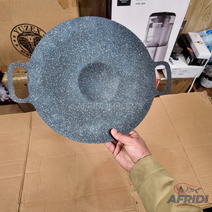 Round, dark grey speckled non-stick griddle with two handles and a central raised area.