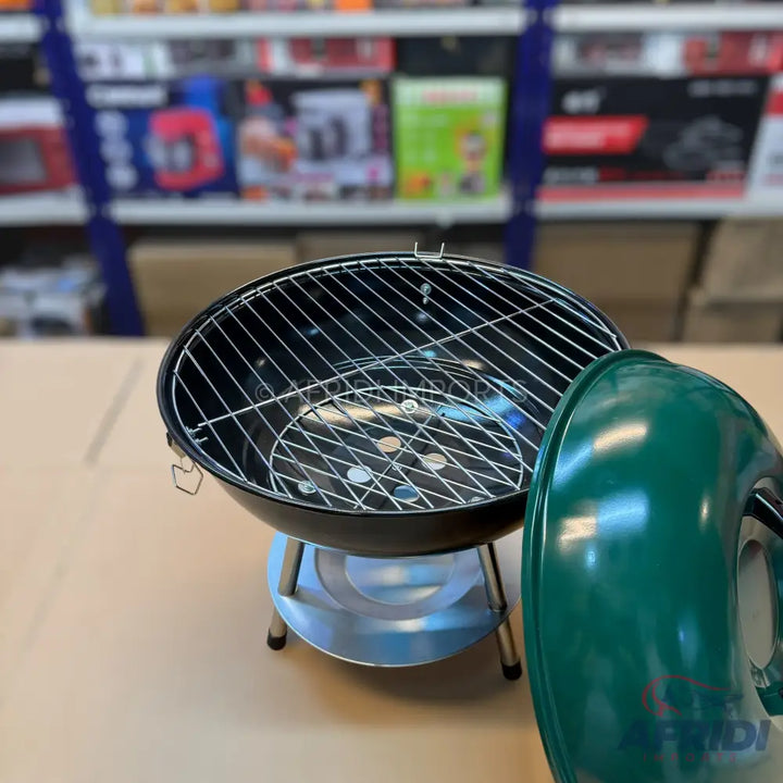 A black, round, portable charcoal grill with a removable grate and a dark green lid.