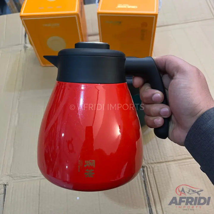 Red insulated beverage carafe with a black handle and spout.