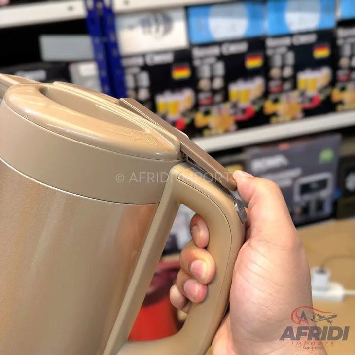 A hand holding a beige electric kettle.