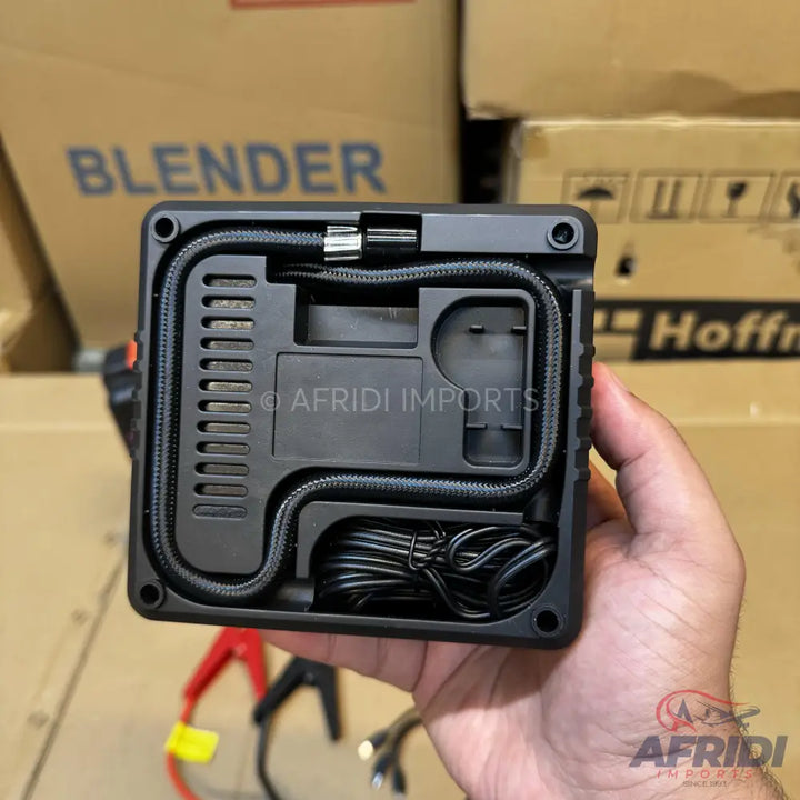 Portable black air compressor with integrated hose and power cable.