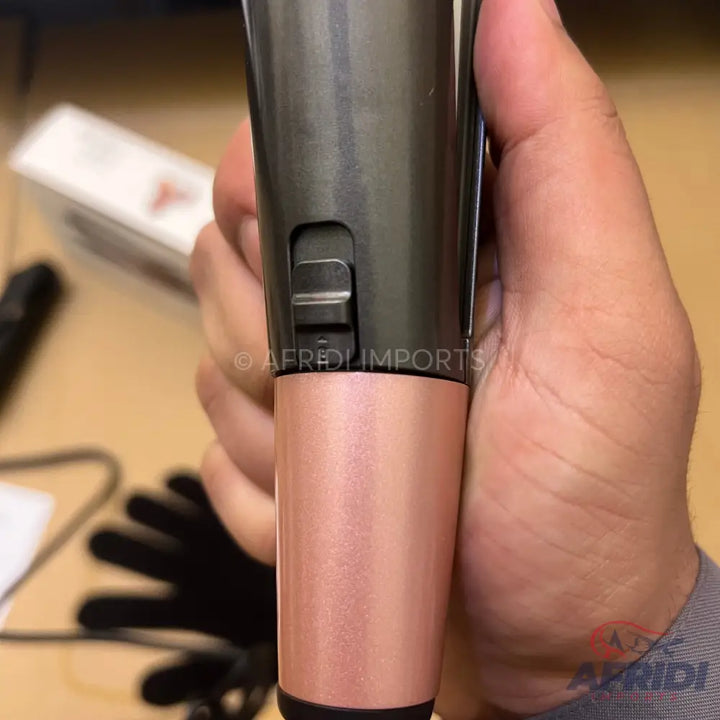 A handheld microphone with a dark grey body and a rose gold lower section, featuring a black slider switch.