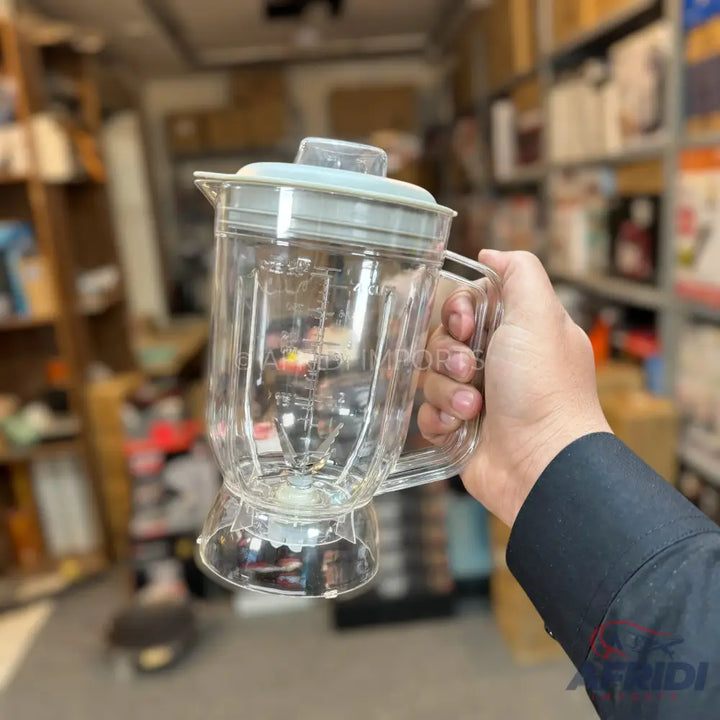 A transparent blender jar with a light blue lid and a handle.