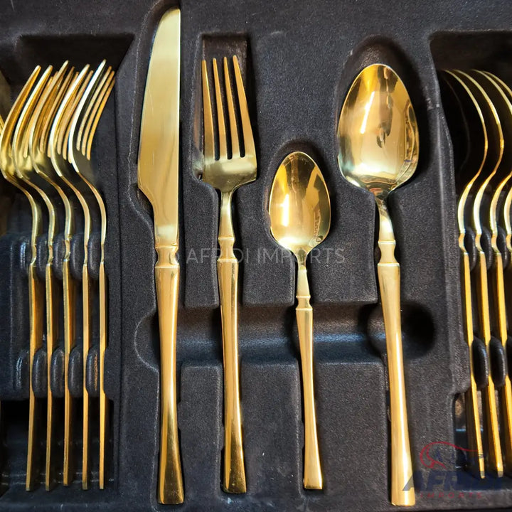 A set of gold-colored flatware, including forks, knives, and spoons, arranged in a fitted case.