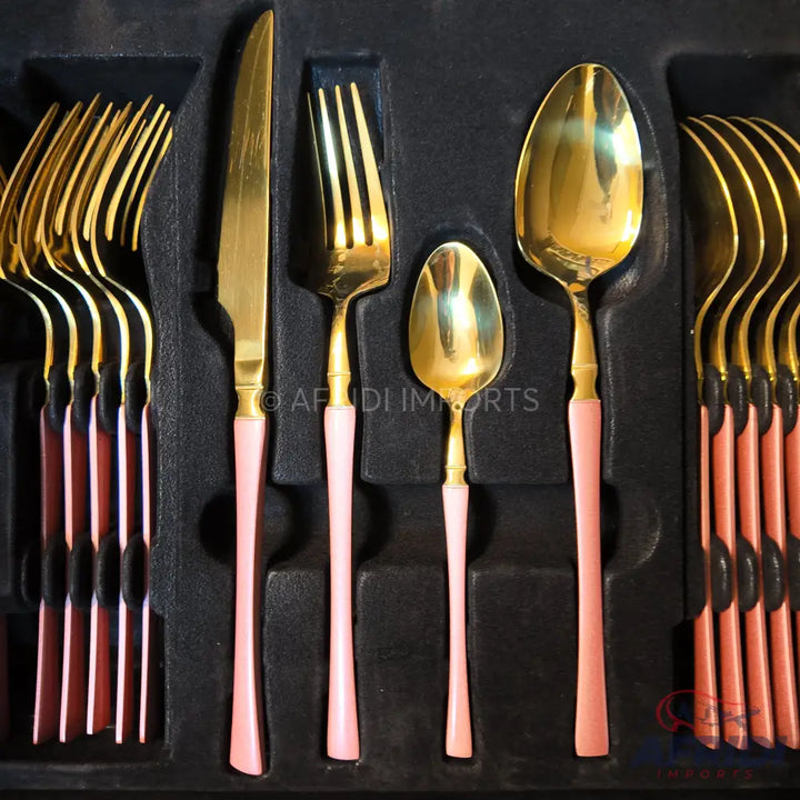 A set of gold-colored flatware with light pink handles, including knives, forks, and spoons.