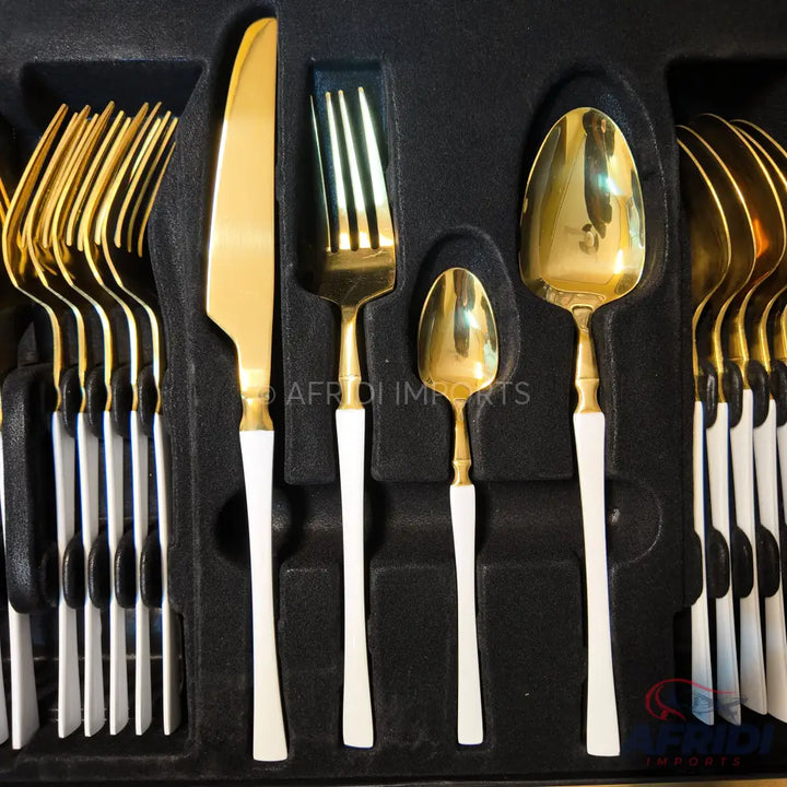 A set of gold and white handle cutlery in a black presentation box.