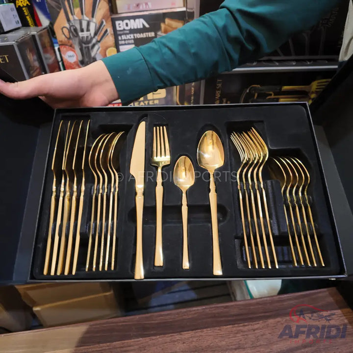 A boxed set of golden-colored flatware, including knives, forks, and spoons.