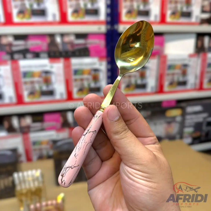 Gold-colored spoon with a pink and white marbled handle.