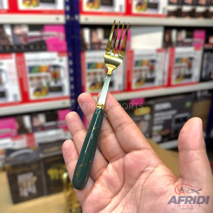 A gold-colored fork with a dark green, marbled handle.