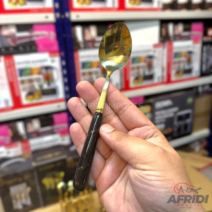 A golden spoon with a black and gold marbled handle.