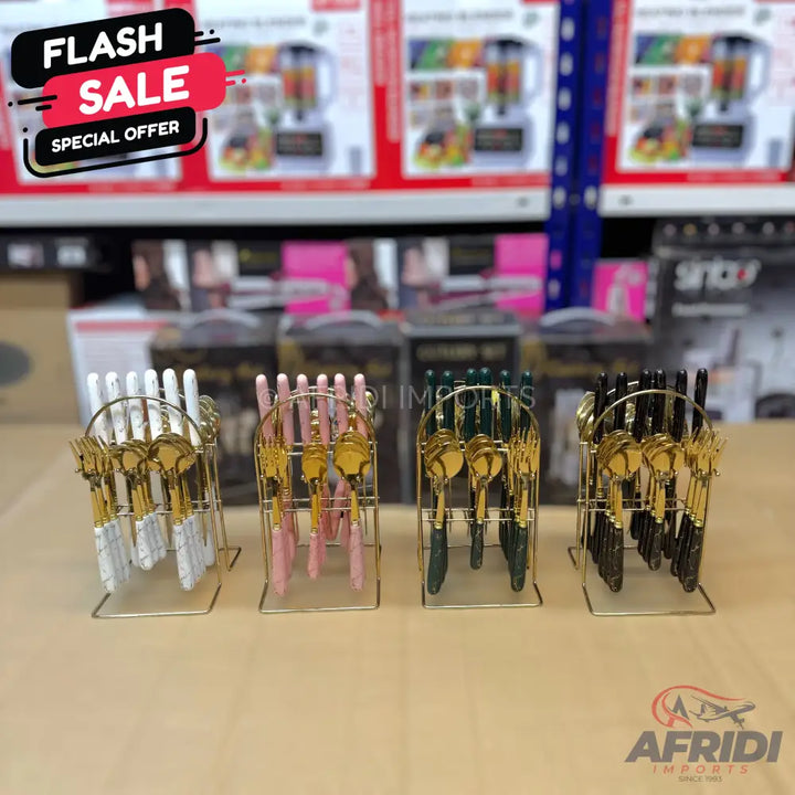 Sets of gold-colored cutlery with handles in white, pink, green, and black, displayed in individual standing racks.
