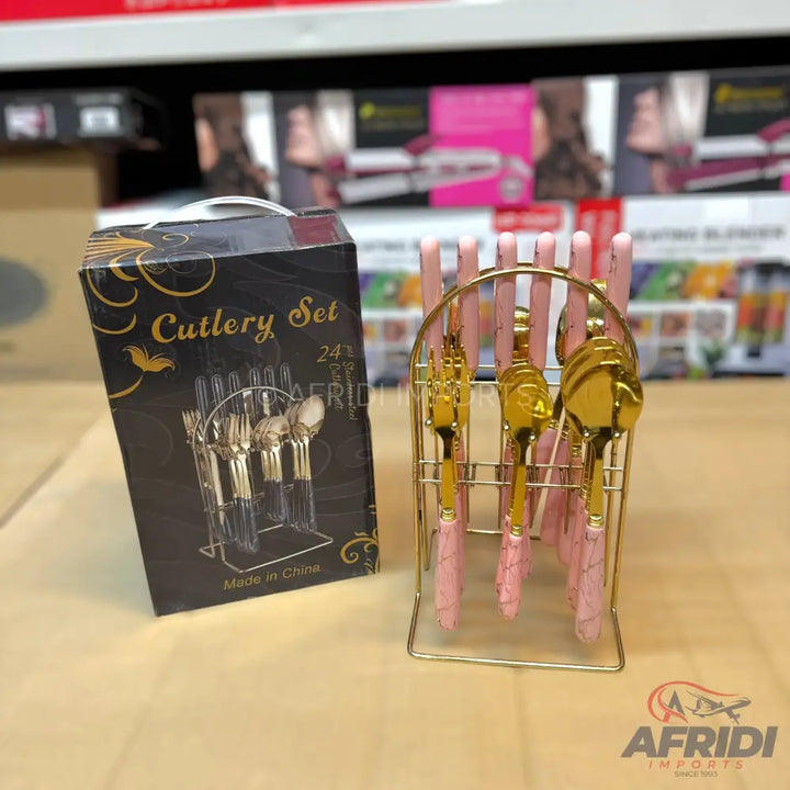 A 24-piece gold-colored cutlery set with pink handles and a metal stand.
