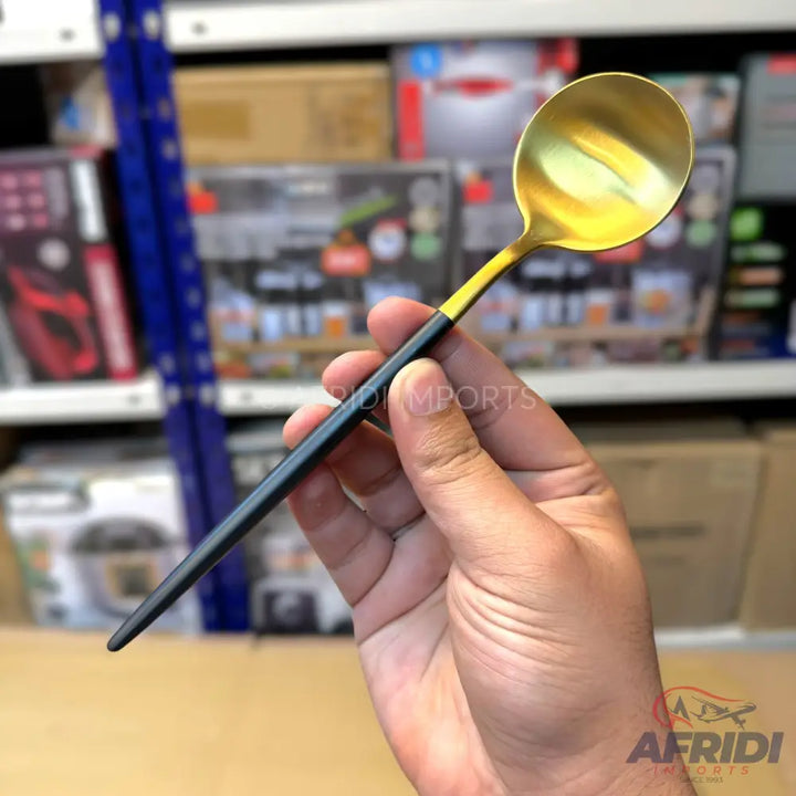 A gold and black handled serving spoon.